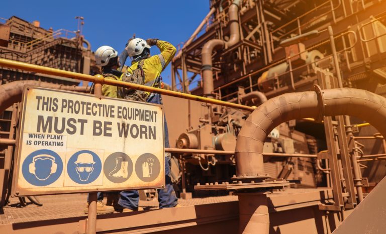 PPE sign on a construction site stating that 'protective equipment must be worn'