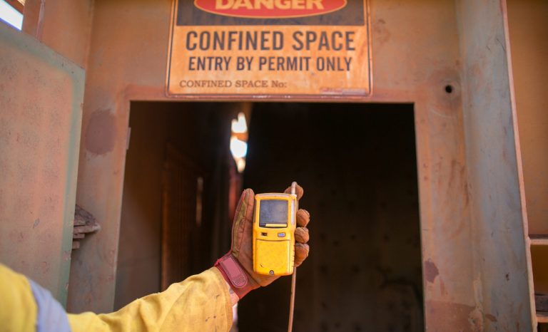 A person holds a thermometer near a door, preparing to measure the temperature before going inside.